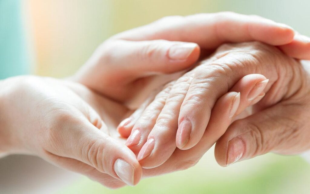 Compassionate individual holding the hand of an elderly person, symbolising support related to Court of Protection matters.