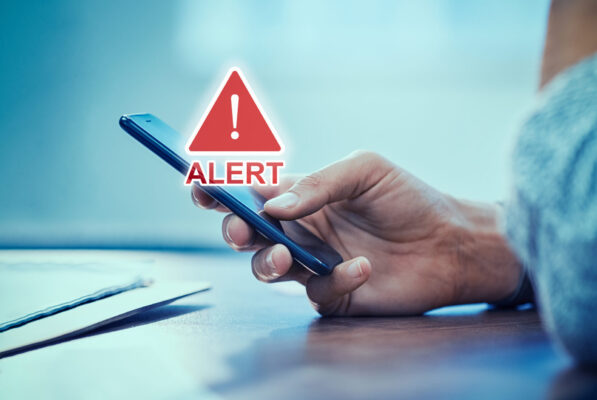 Emergency Alert security message on phone Emergency alert security message pop up on phone screen. Woman hand holding smartphone while receiving an official emergency alert notification from government.
