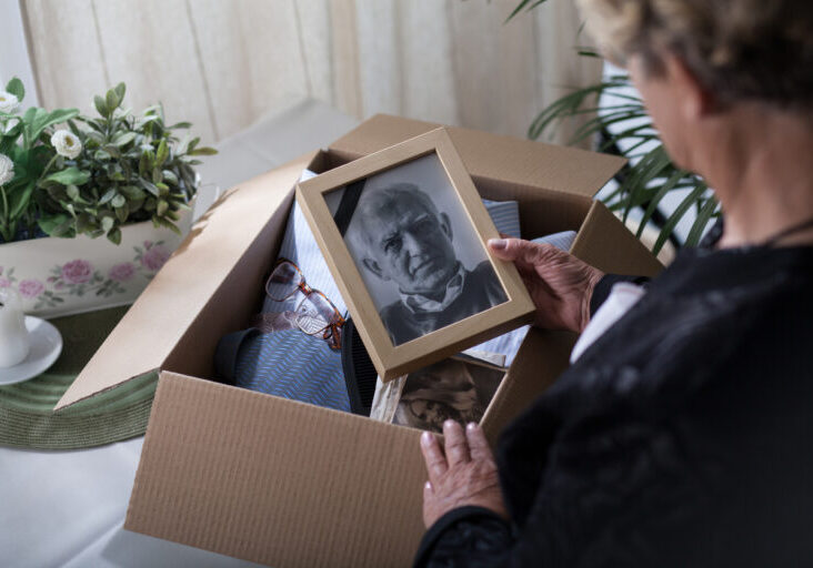 Elderly-woman-looking-through-box-of-late-husbands-items