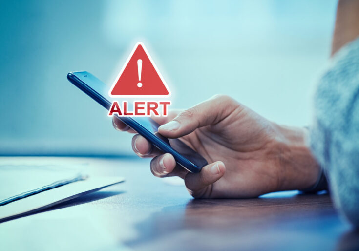Emergency alert security message pop up on phone screen. Woman hand holding smartphone while receiving an official emergency alert notification from government.