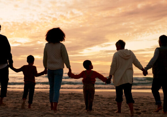 Family, travel and holding hands at beach in summer for relax, walking and vacation as silhouette. People, children and back at ocean with solidarity for holiday, trust and love together by sunset