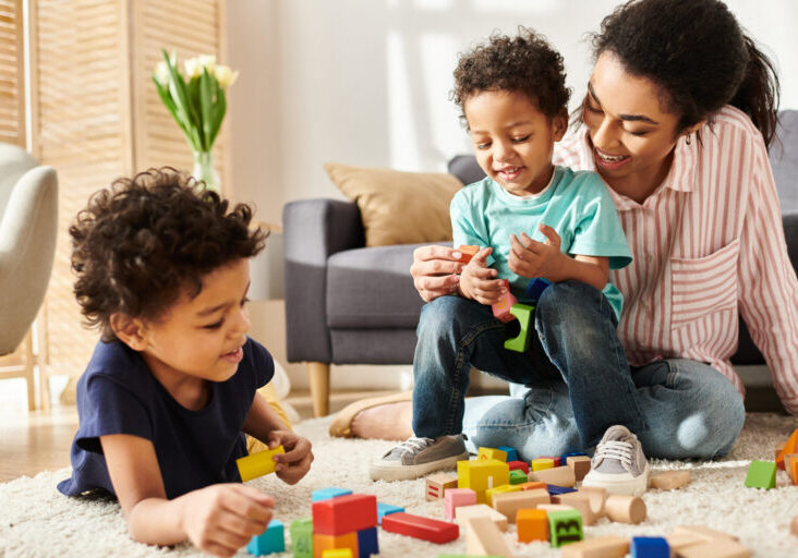 A mother engages with her two sons, fostering creativity and imagination with colorful toys.
