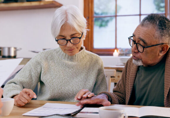 Couple, paperwork and reading for insurance in retirement, planning and bills or documents. Senior people, marriage and communication or discussion for future, saving and finance in kitchen at home